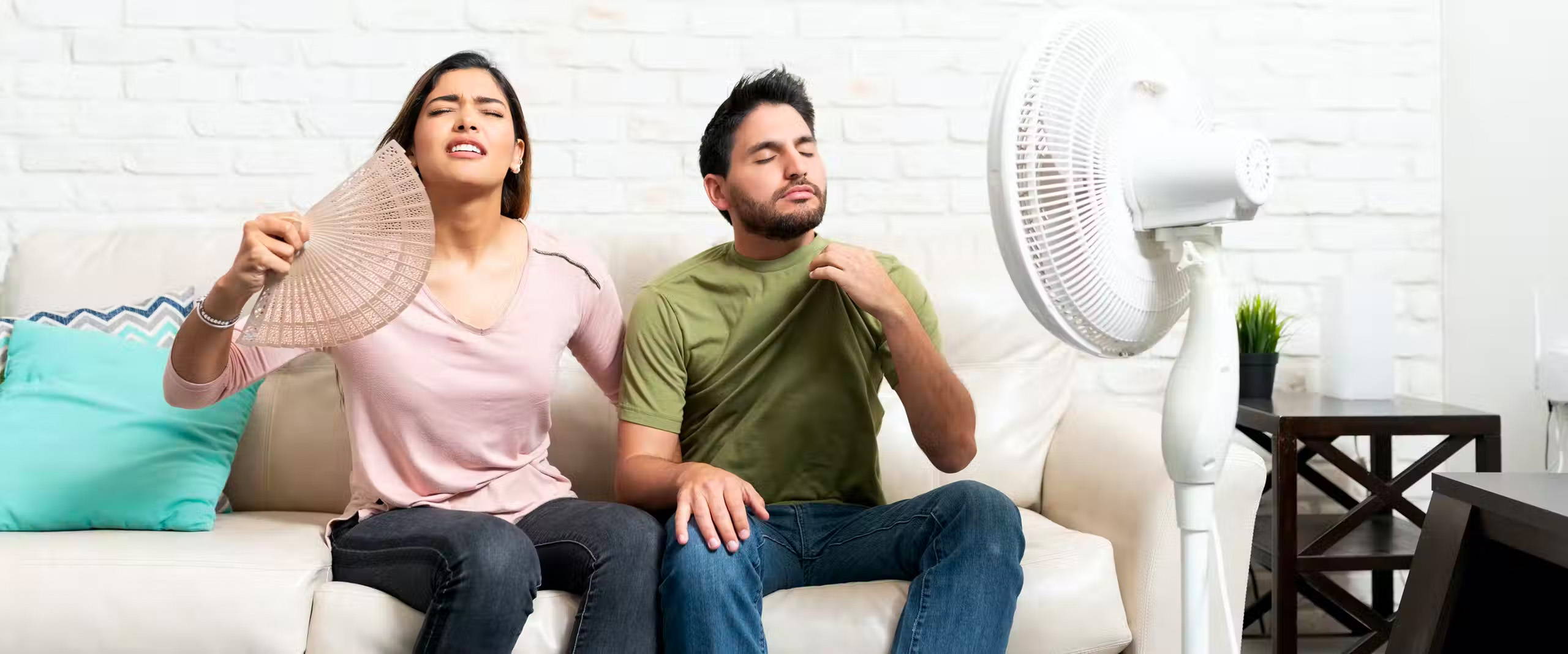 Woman and man fanning themselves in a hot room