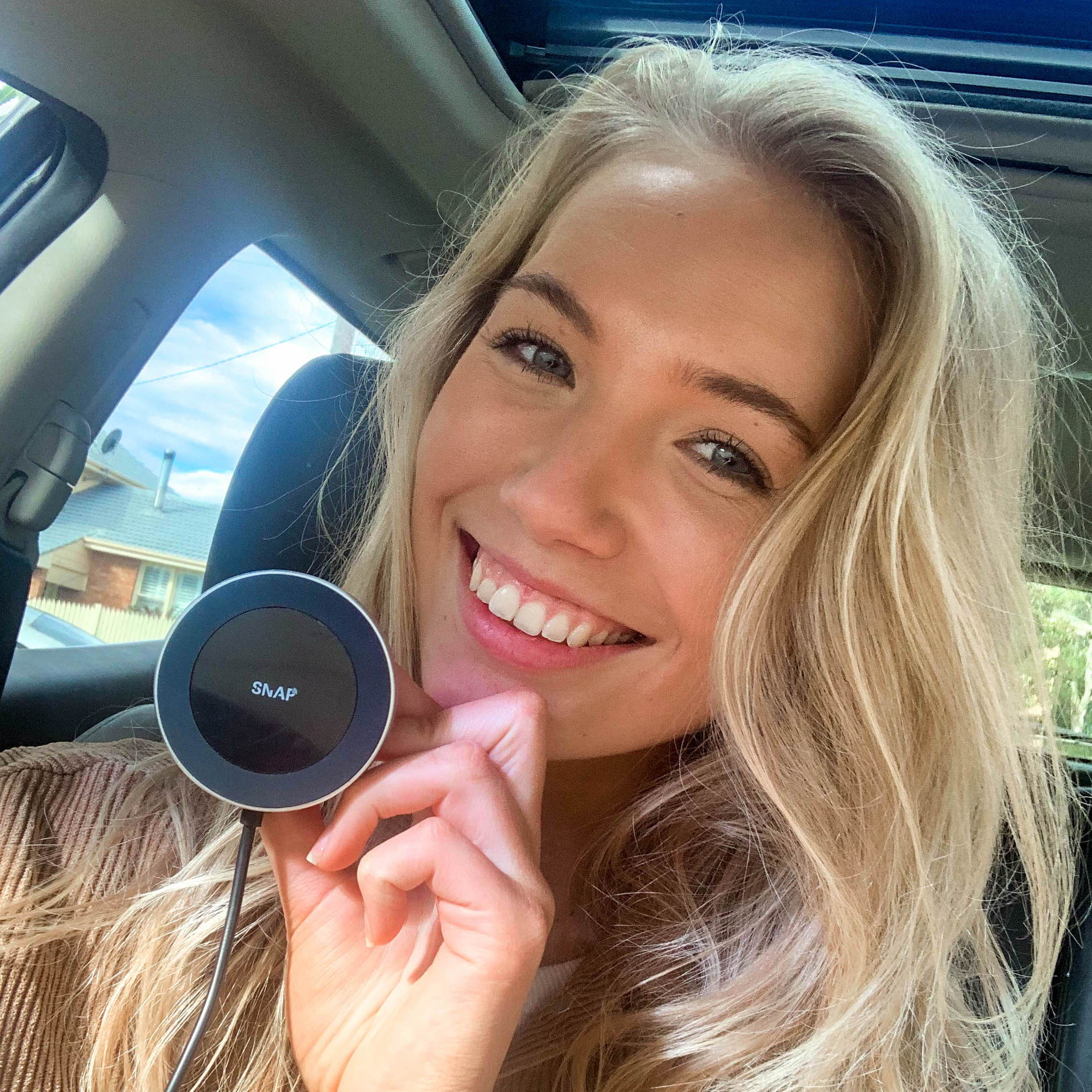 lady holding snapmount wireless car charger in her car
