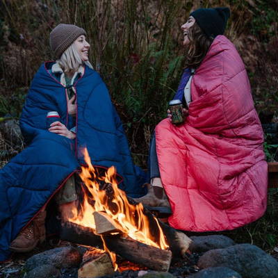 Two women wrapped in blankets around fire