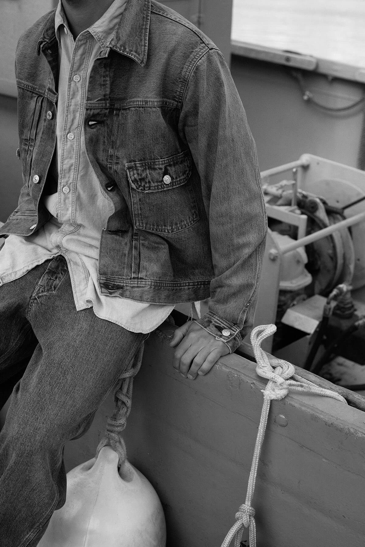 A person in a denim jacket sitting on a boat.