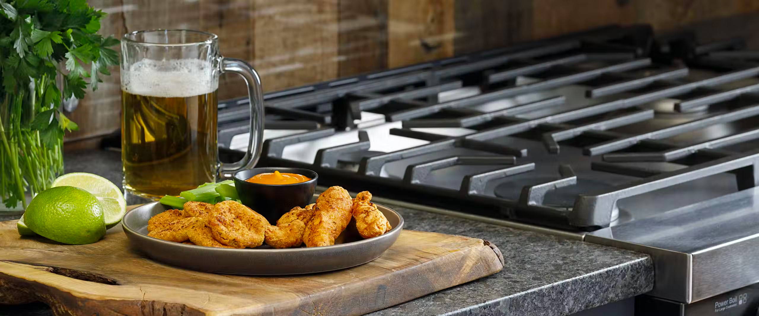 Plate of air-fried snacks next to a gas range, with a beer in the background