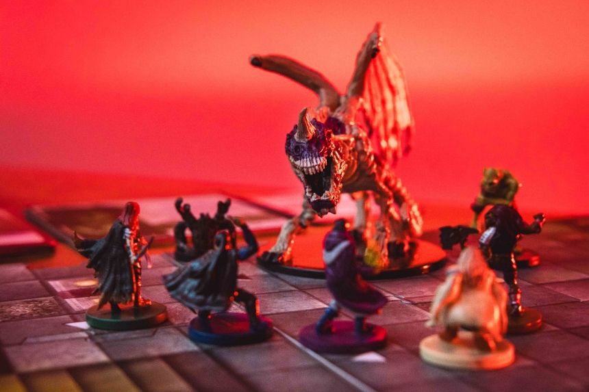 Colorful tabletop miniatures on a game board with dramatic lighting.