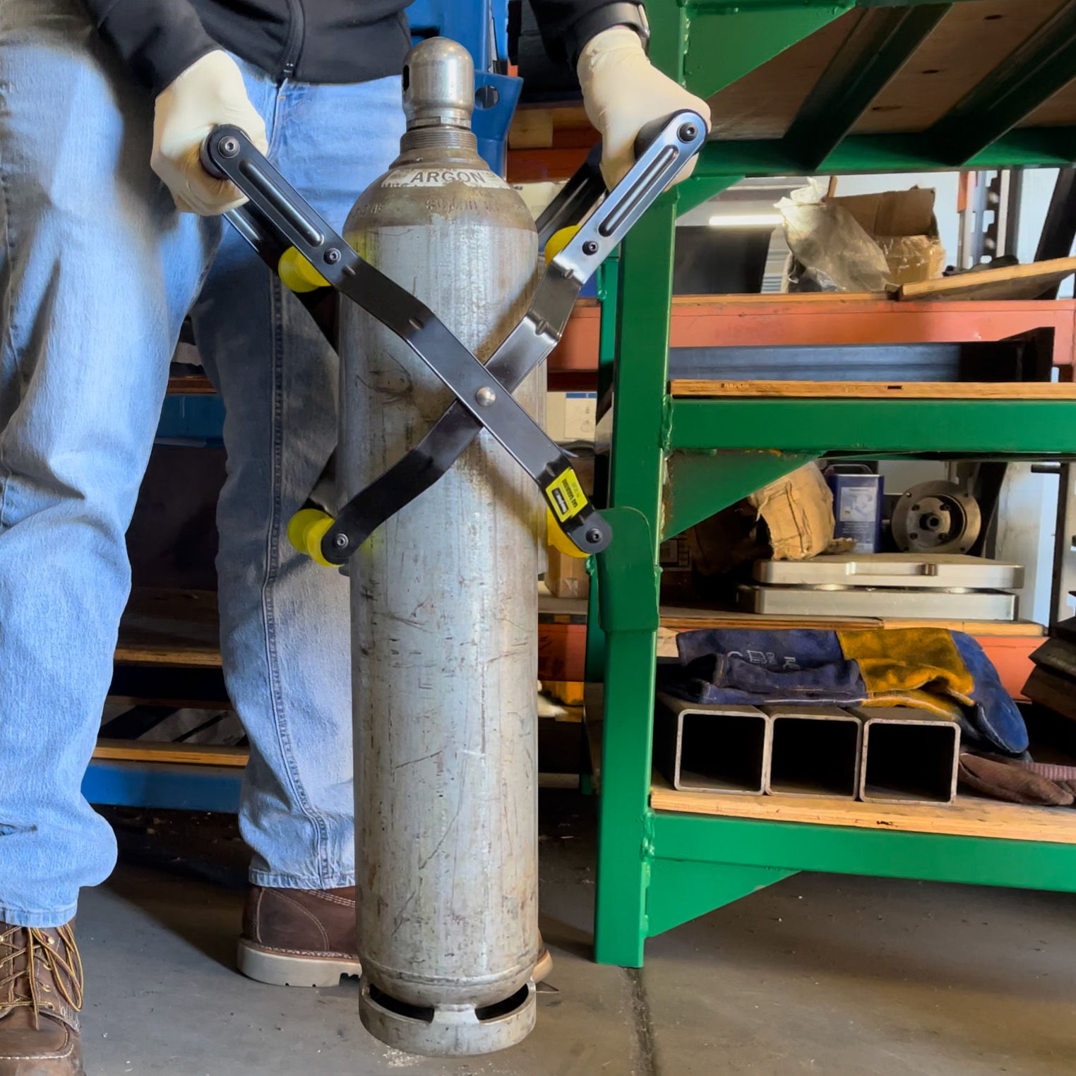 Person holding two saws against a metal cylinder in a workshop setting.