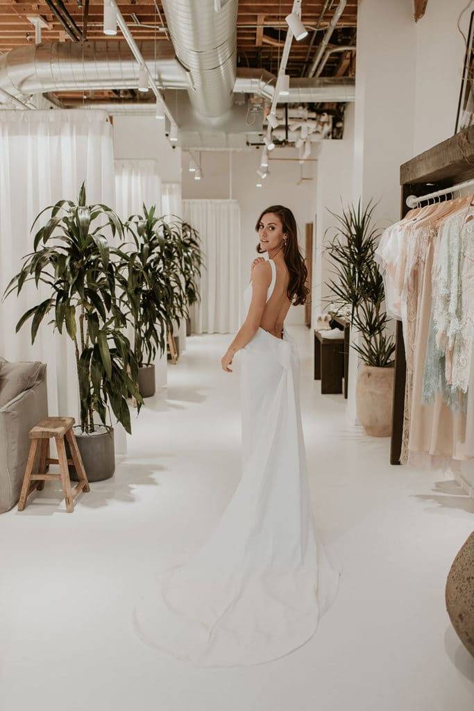 Bride inside the Denver Grace Loves Lace bridal showroom wearing a low back silk dress