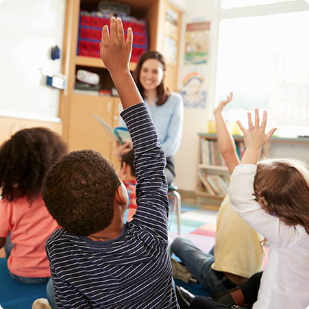 children with their hands up in school