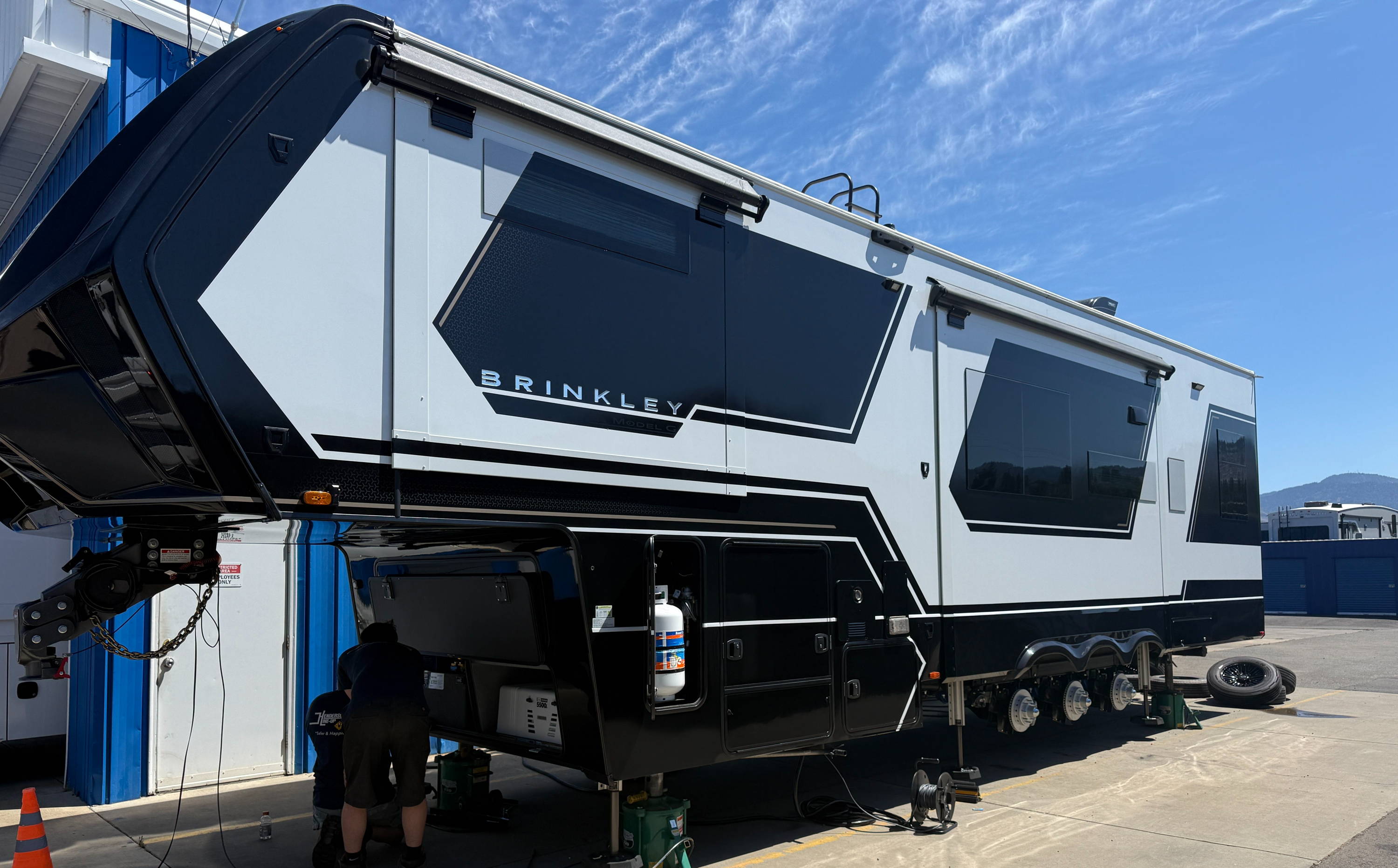 A large modern RV parked on a driveway under a clear blue sky.