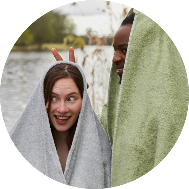 Zwei Menschen in Handtücher eingehüllt am See