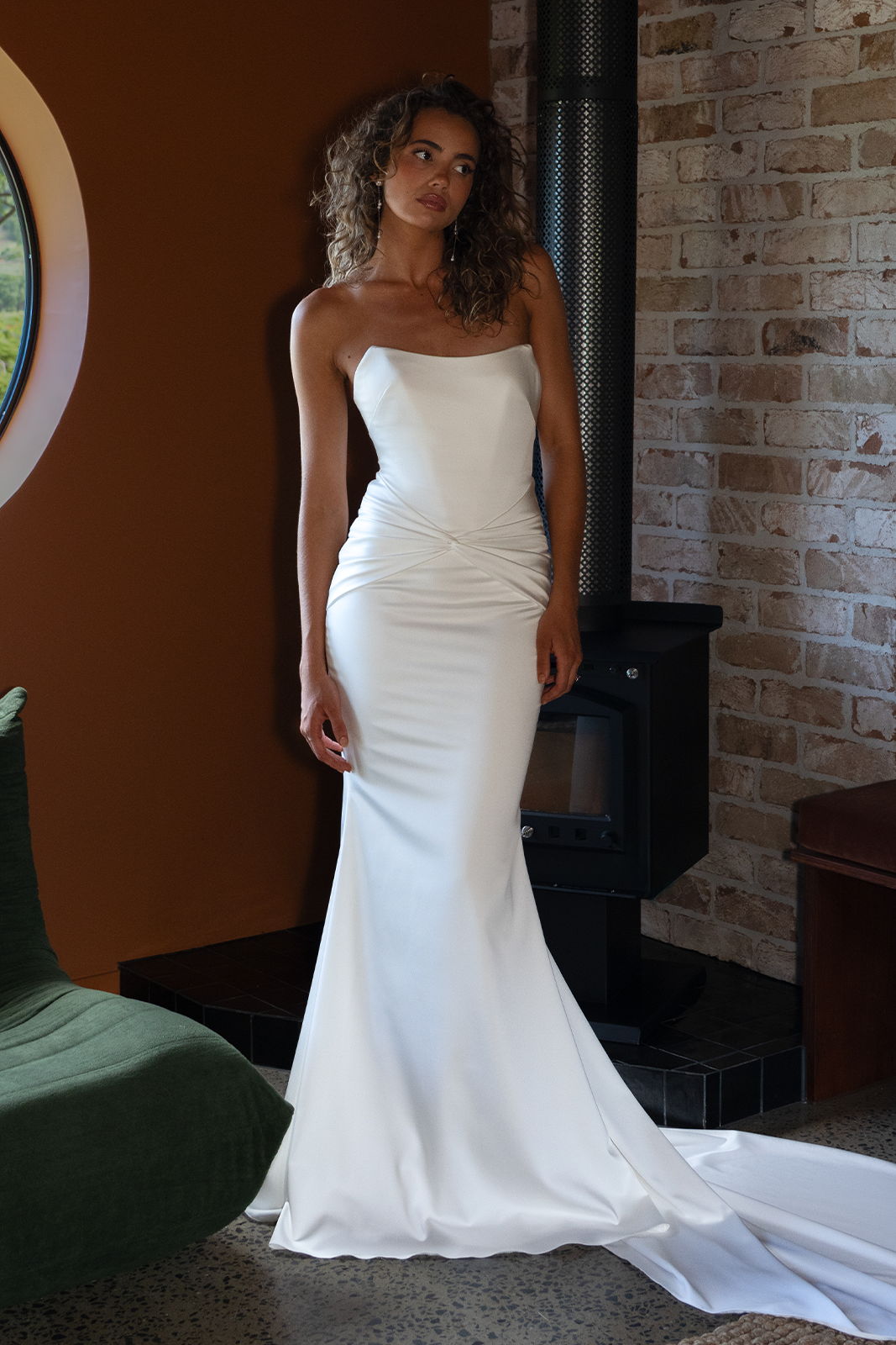 Model in a white strapless gown posing indoors.
