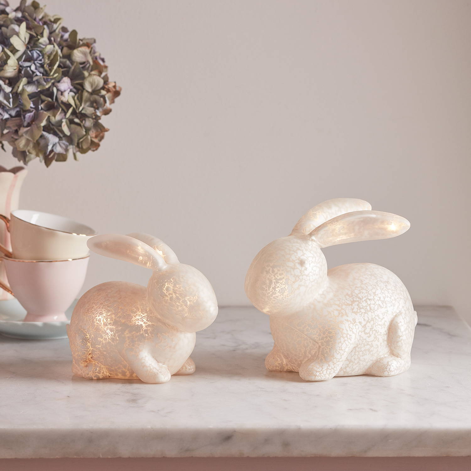 Un ensemble de 2 Décos de Pâques, Lapins Lumineux Blancs en Verre Moucheté sur un comptoir de cuisine.