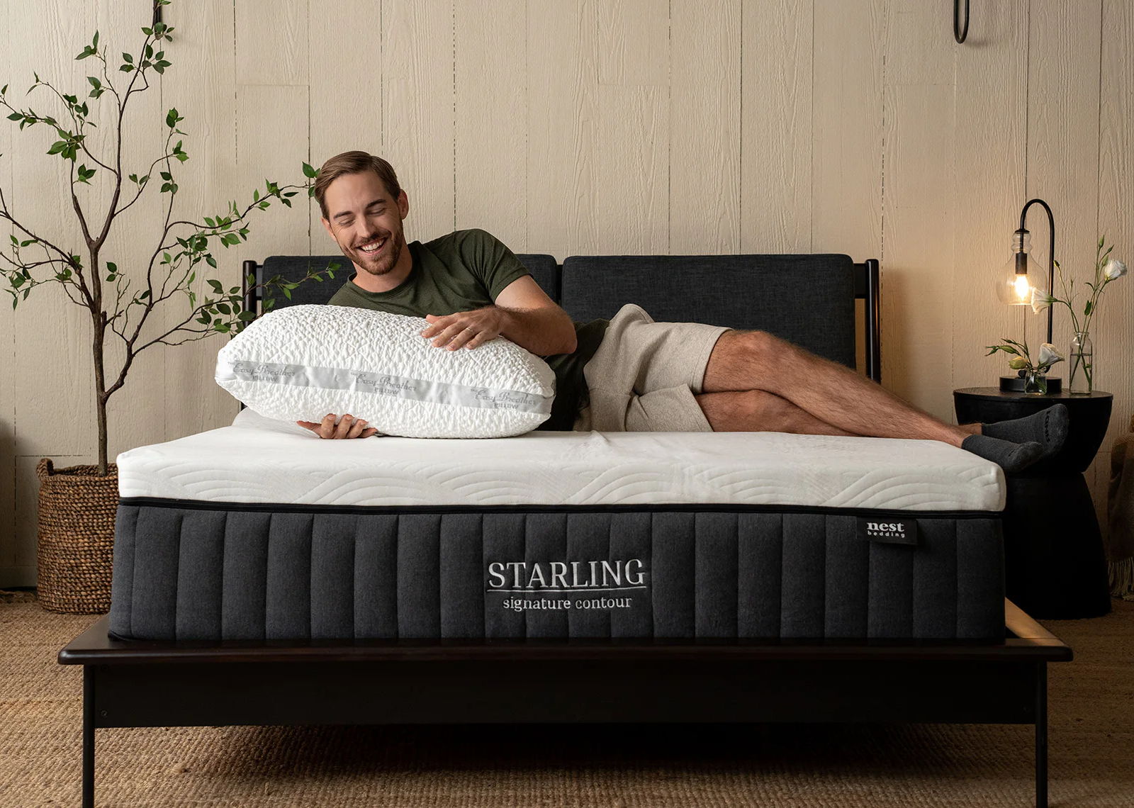 man happily laying on a starling signature contour mattress and holding an easy breather pillow