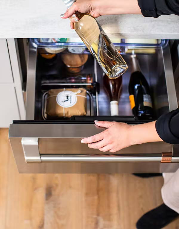 Woman pulling wine out of drawer refrigerator