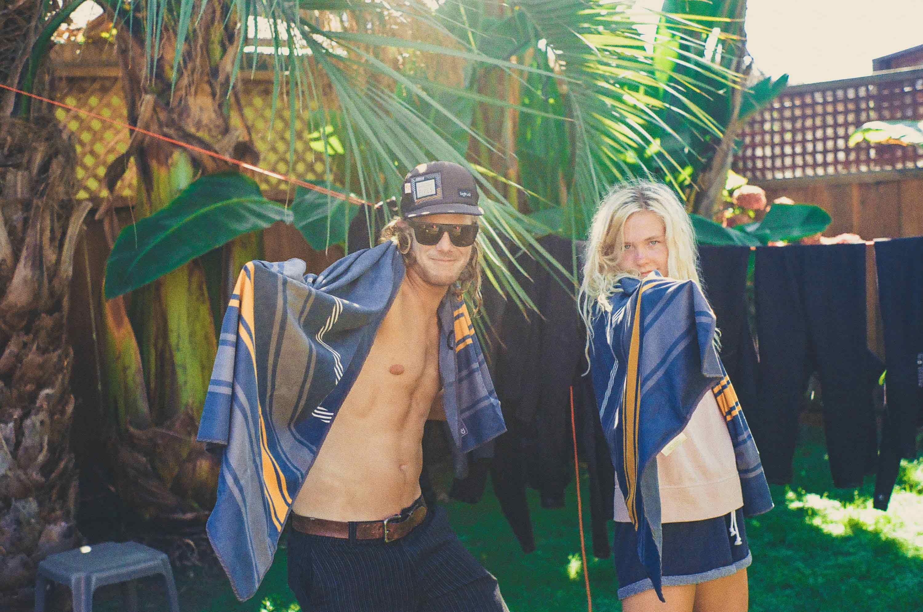 Man and young girl with Rumpl x High Fives towels in front of wetsuits