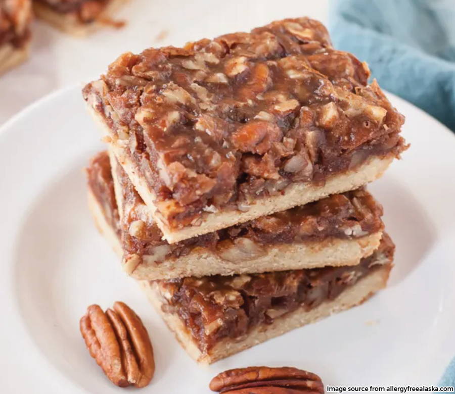 A stack of three pecan pie bars sitting on a plate. 