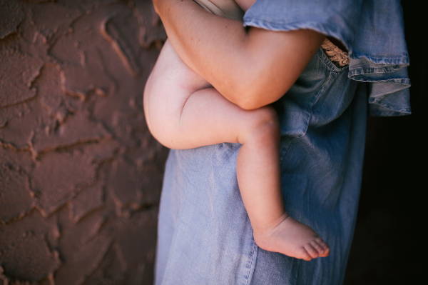 Naked baby on mother's hipwith knees higher than bottom in ergonomic position