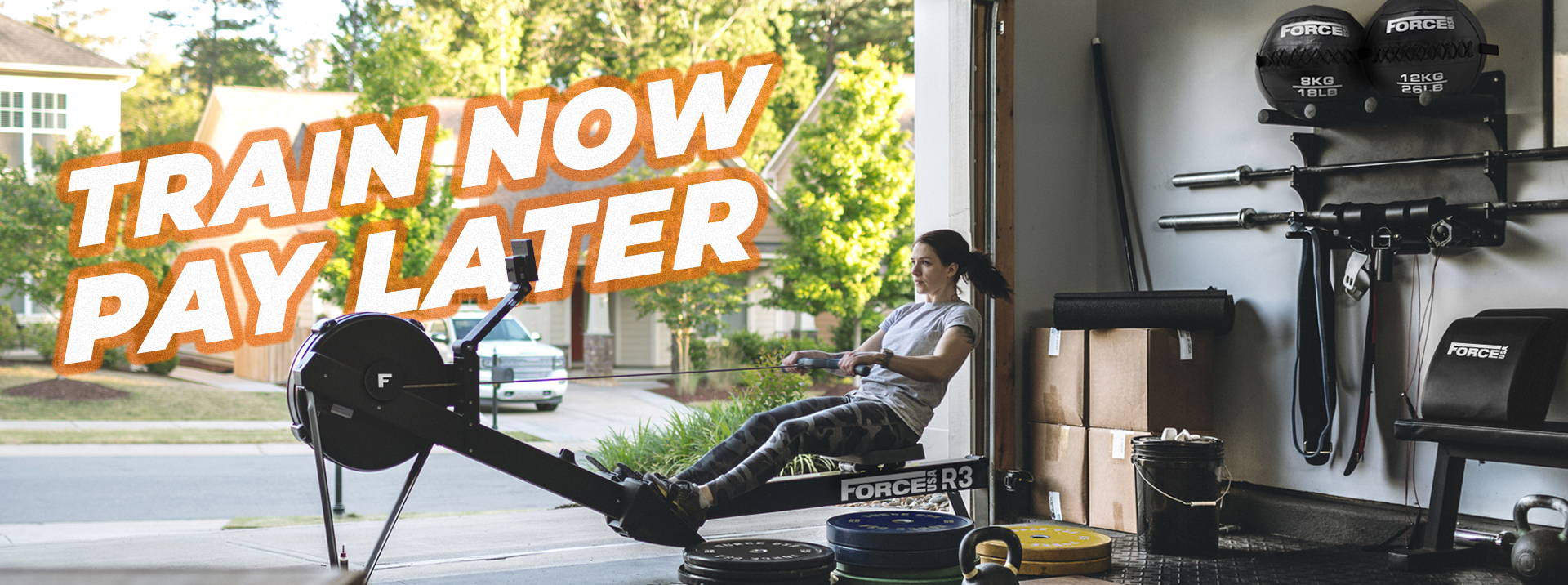 Home gym with equipment and 'TRAIN NOW PAY LATER' offer highlighted, featuring a focused woman using a rowing machine in a garage setting.
