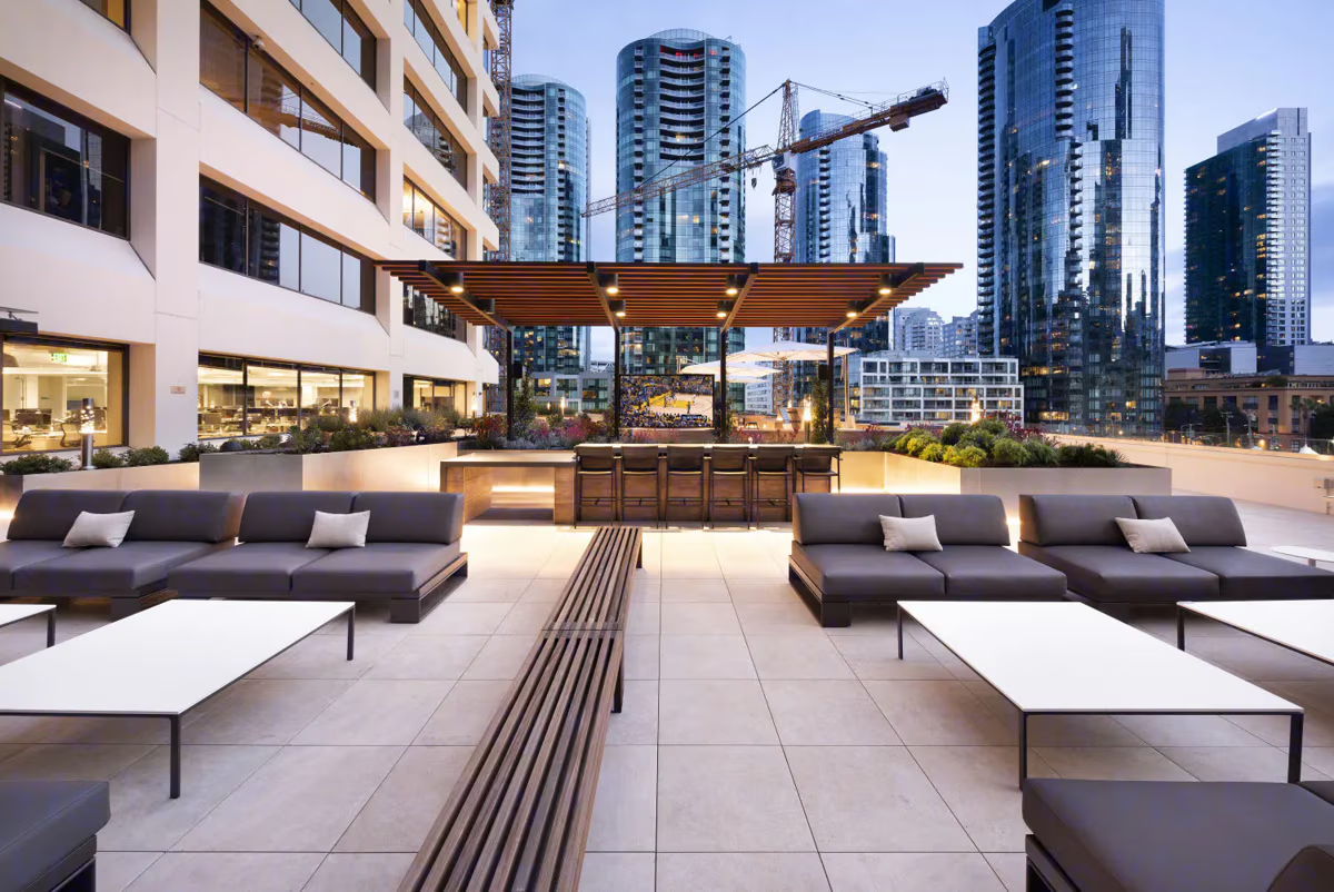 Modern rooftop lounge area with seating and city skyline view.