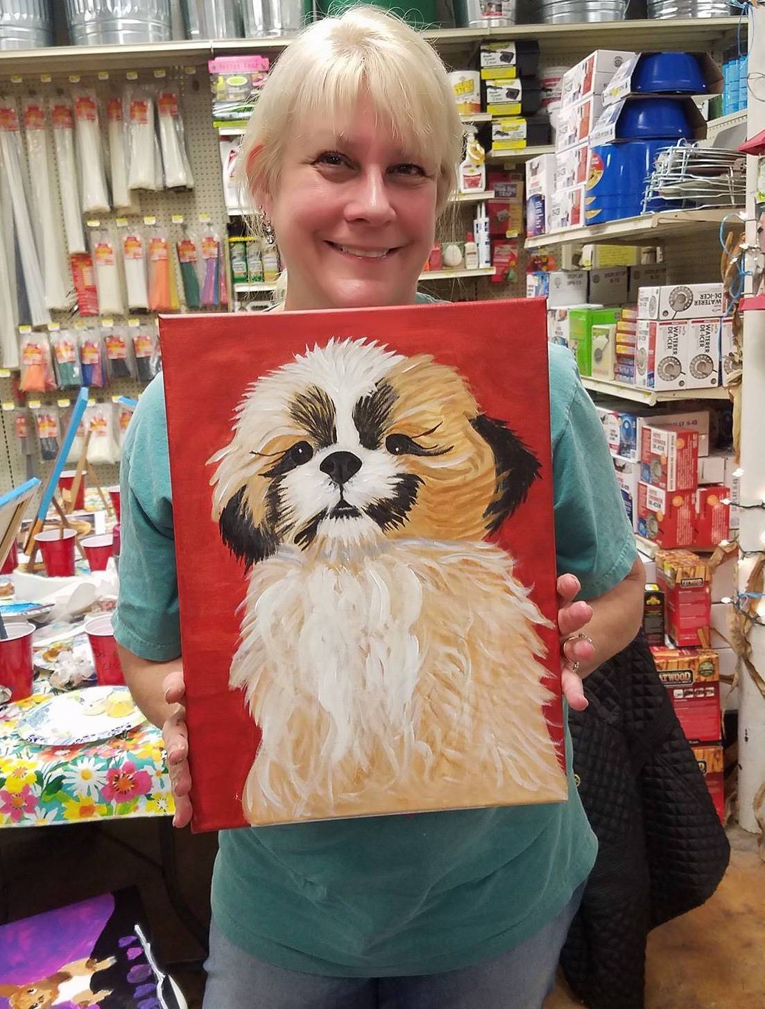 Woman holding a painting from one of the store's classes. 