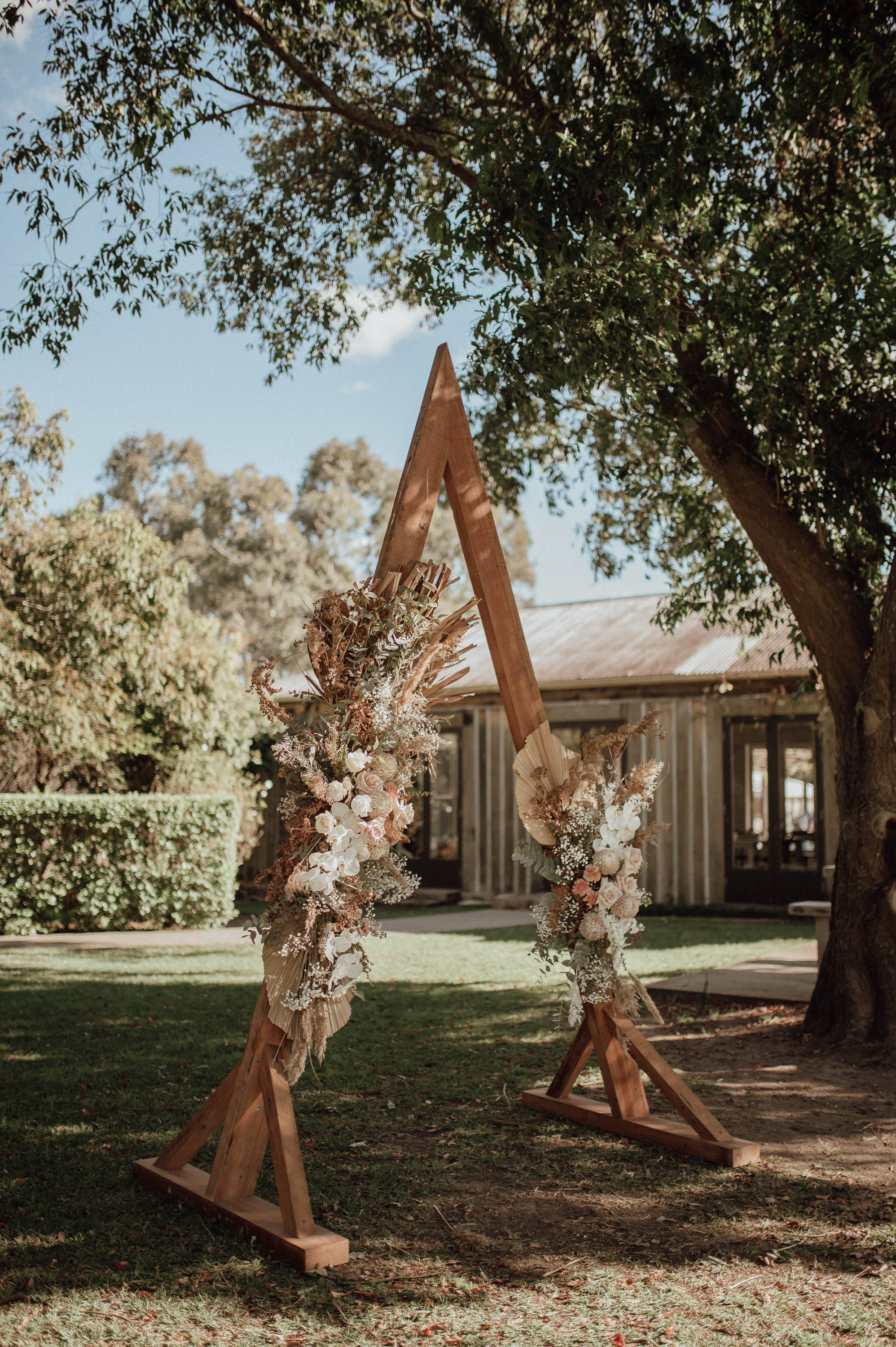 Wooden triangle arbor decorated with white and peach coloured florals