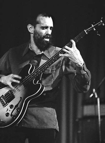 Musician playing an electric bass guitar on stage.