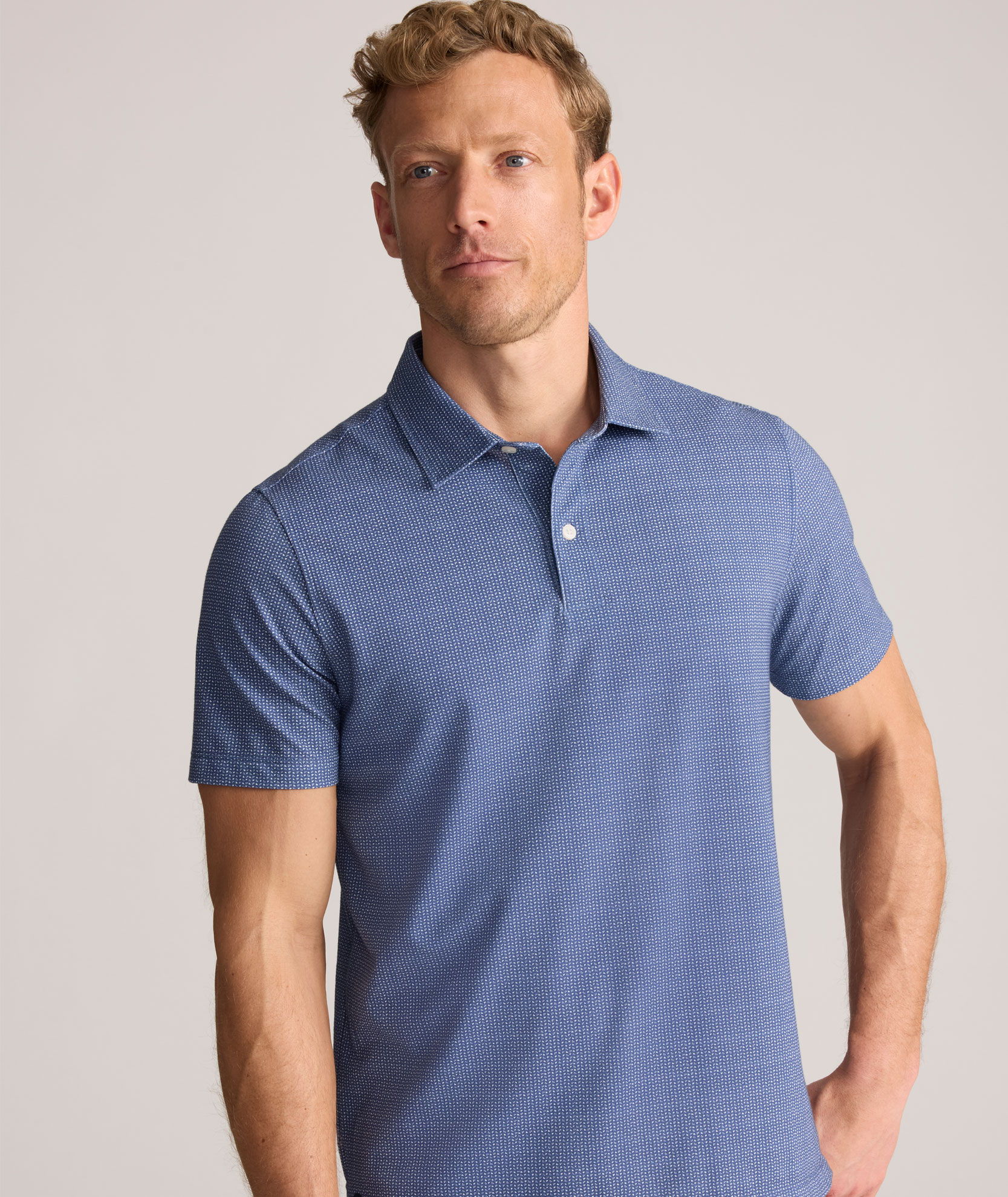 Man wearing a blue polo shirt, looking thoughtfully to the side.