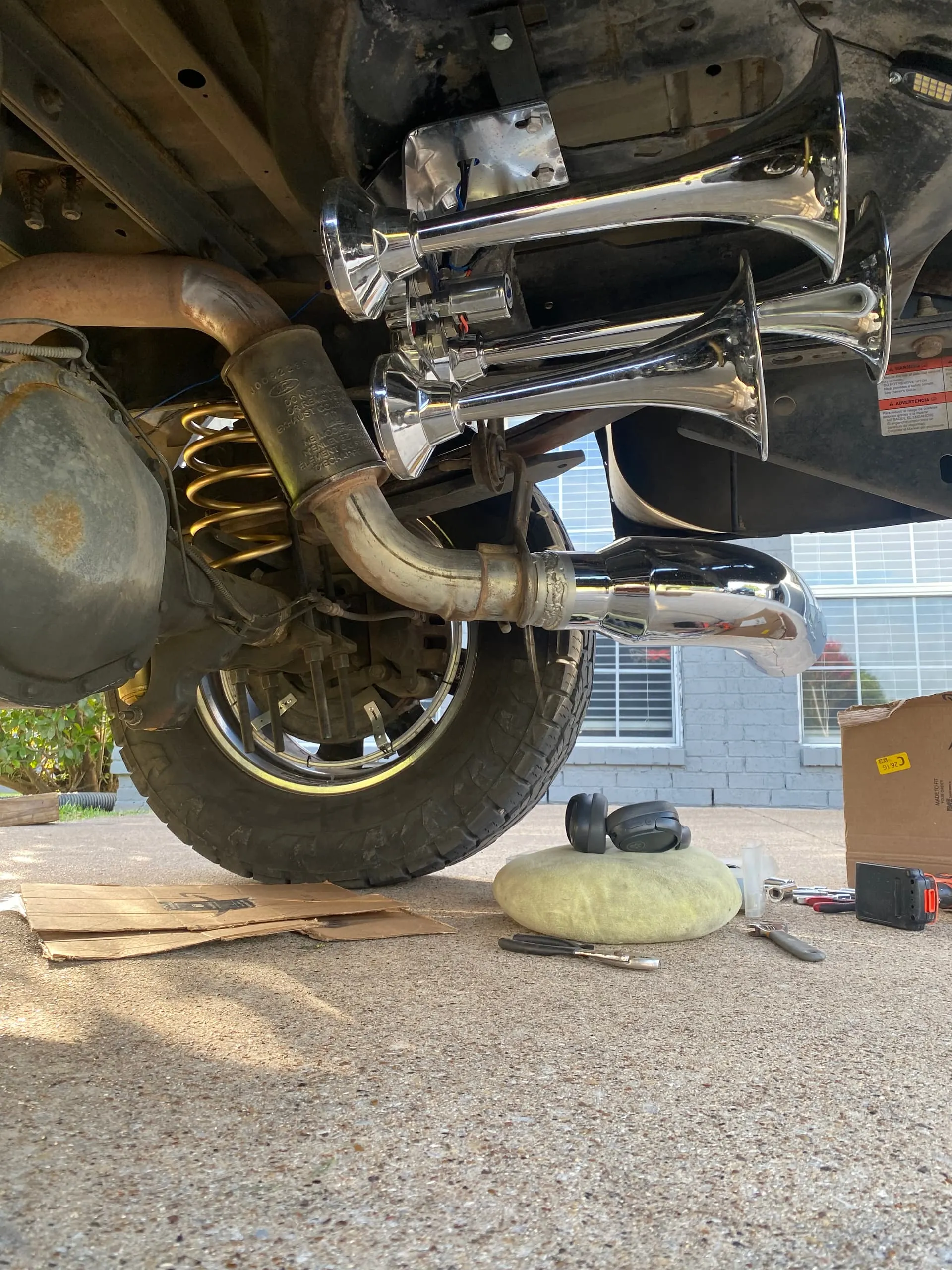 Four chrome train horns installed on the rear undercarriage of Malachi's Ford F250 during installation