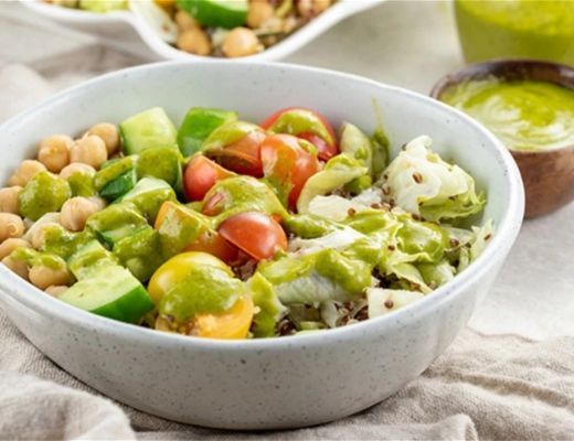 A healthy bowl with chickpeas, vegetables, and green sauce.