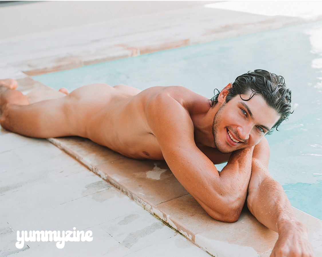Man lounging by a pool, smiling, with water in the background.