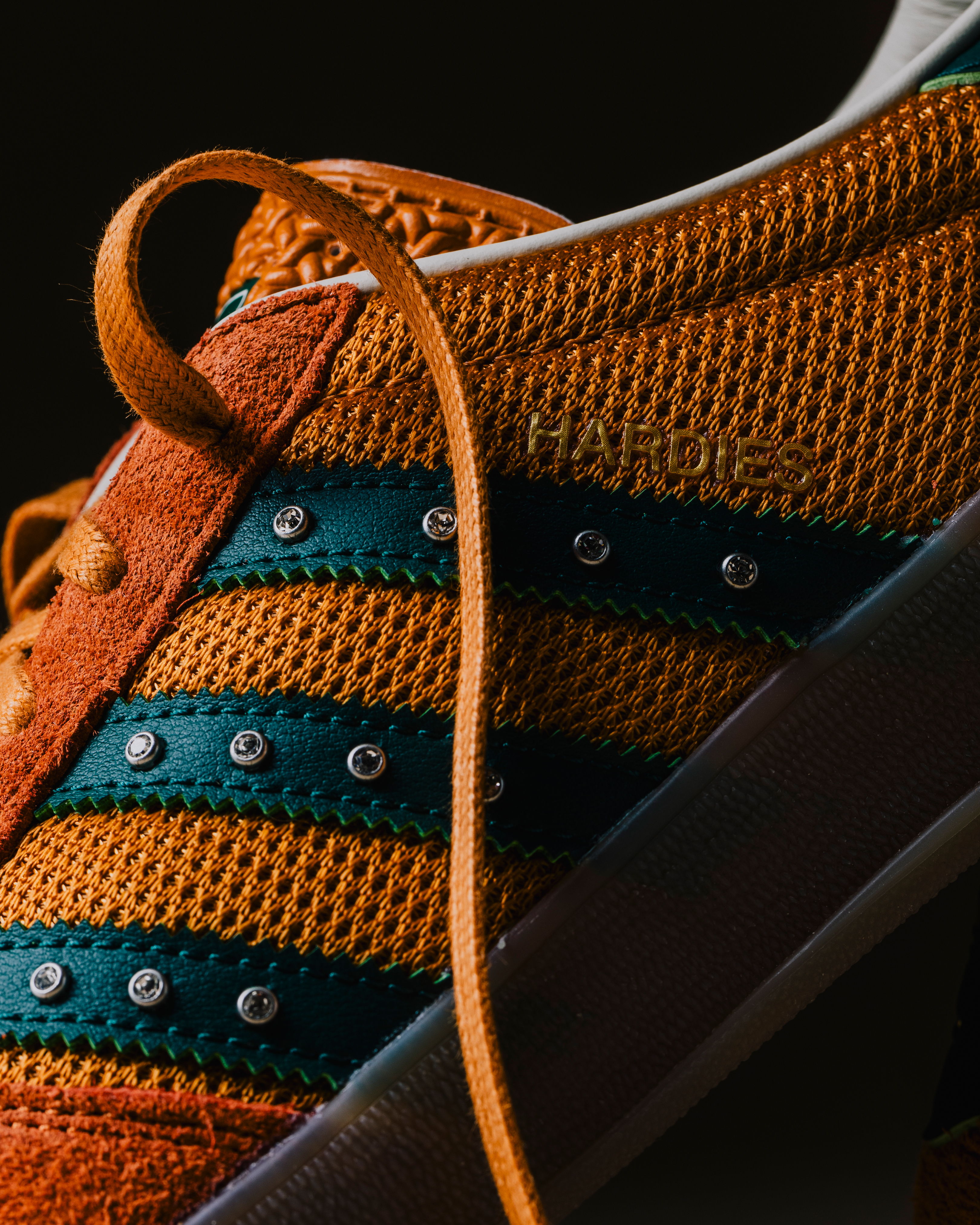 Close-up of an orange sneaker with green stripes and a laced-up shoelace.