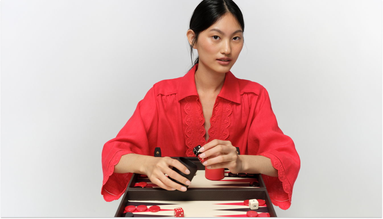 Person in red outfit playing a board game on a table.