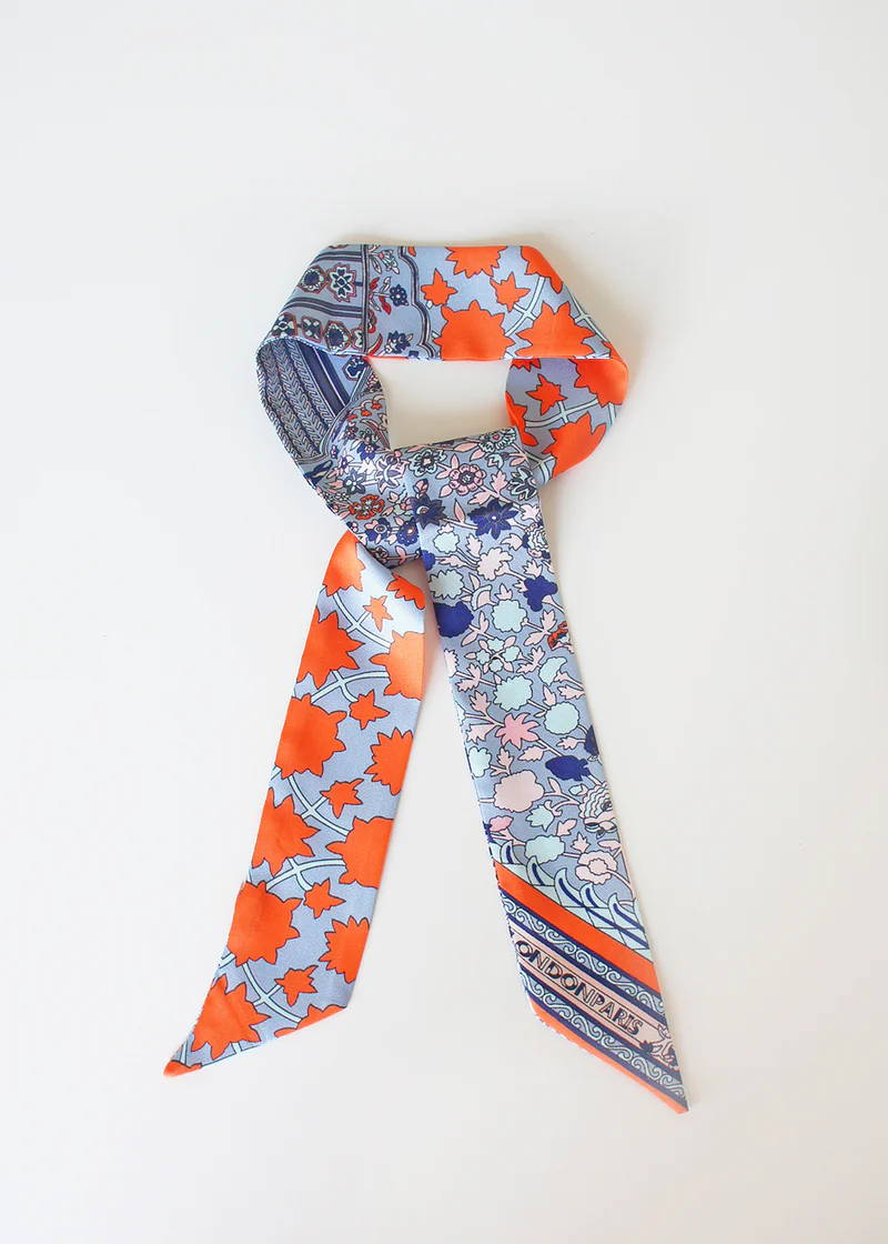 A silk neck scarf with a red and blue botanical pattern 