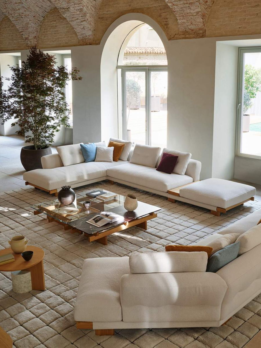 Modern living room with sectional sofa, coffee table, and large windows.