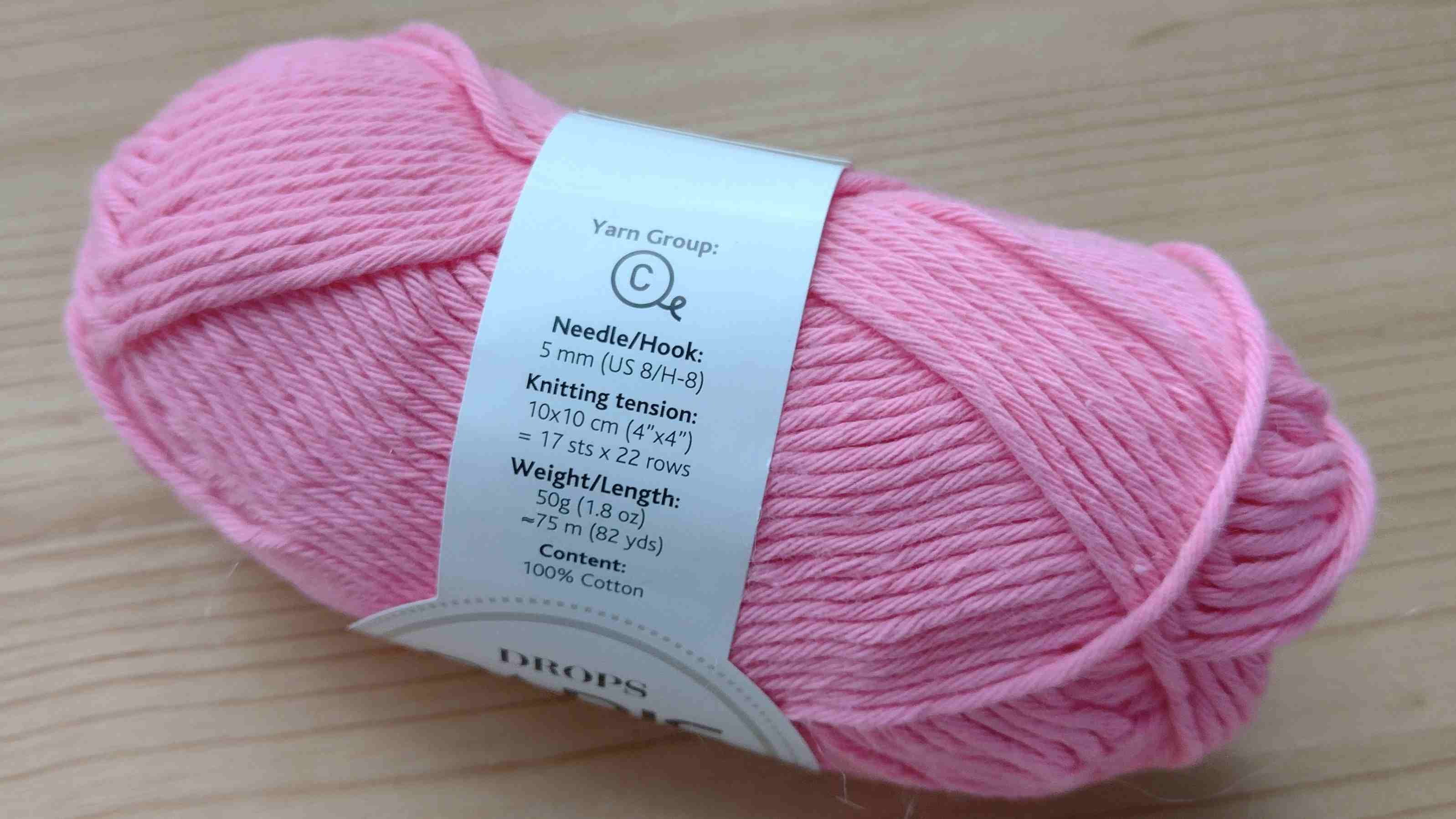 Banderole zur Bestimmung der Häkelnadelgröße an einem rosa Wollknäuel.