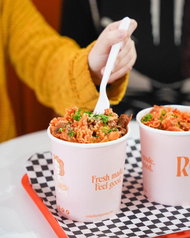 Person holding a white fork over a cup of food.