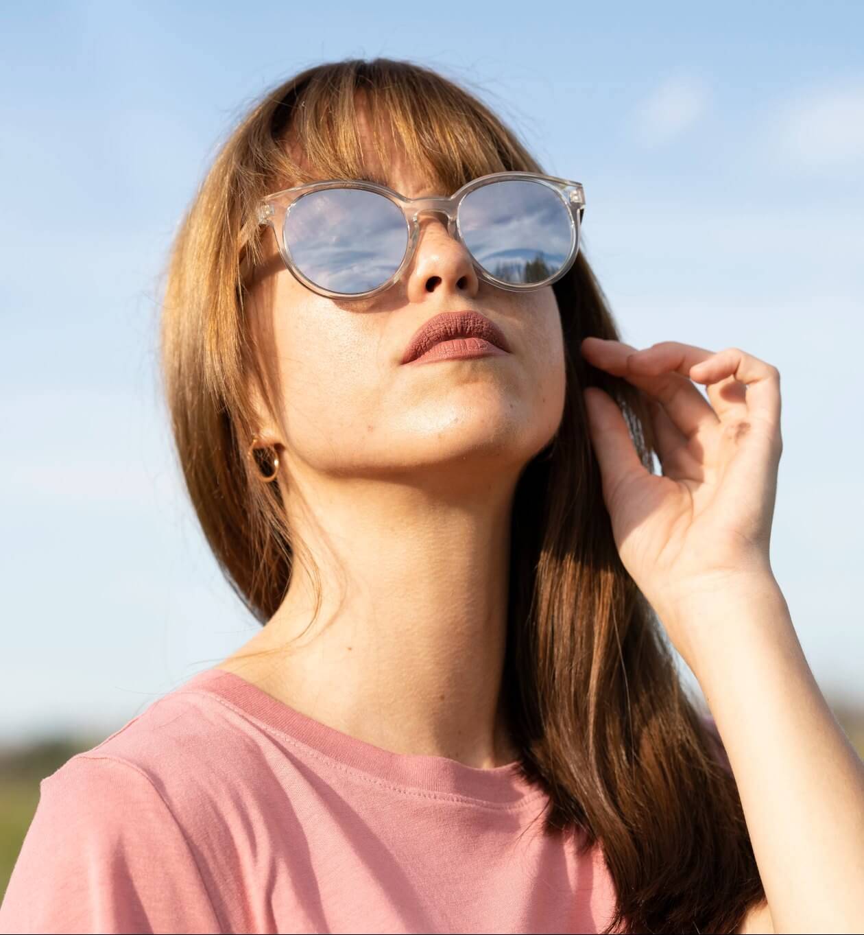 Femme portant des lunettes de soleil réfléchissantes à monture ronde et transparente Groove