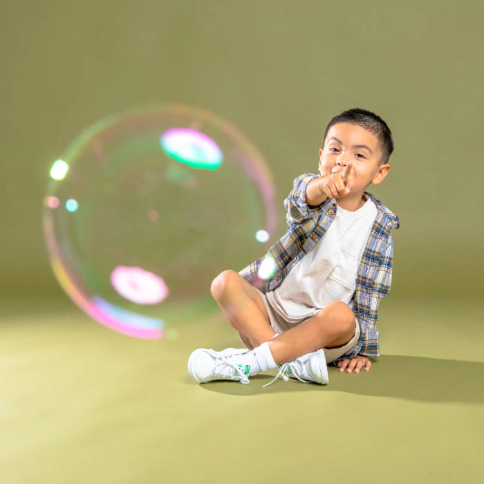 young boy sitting pointing at bubble