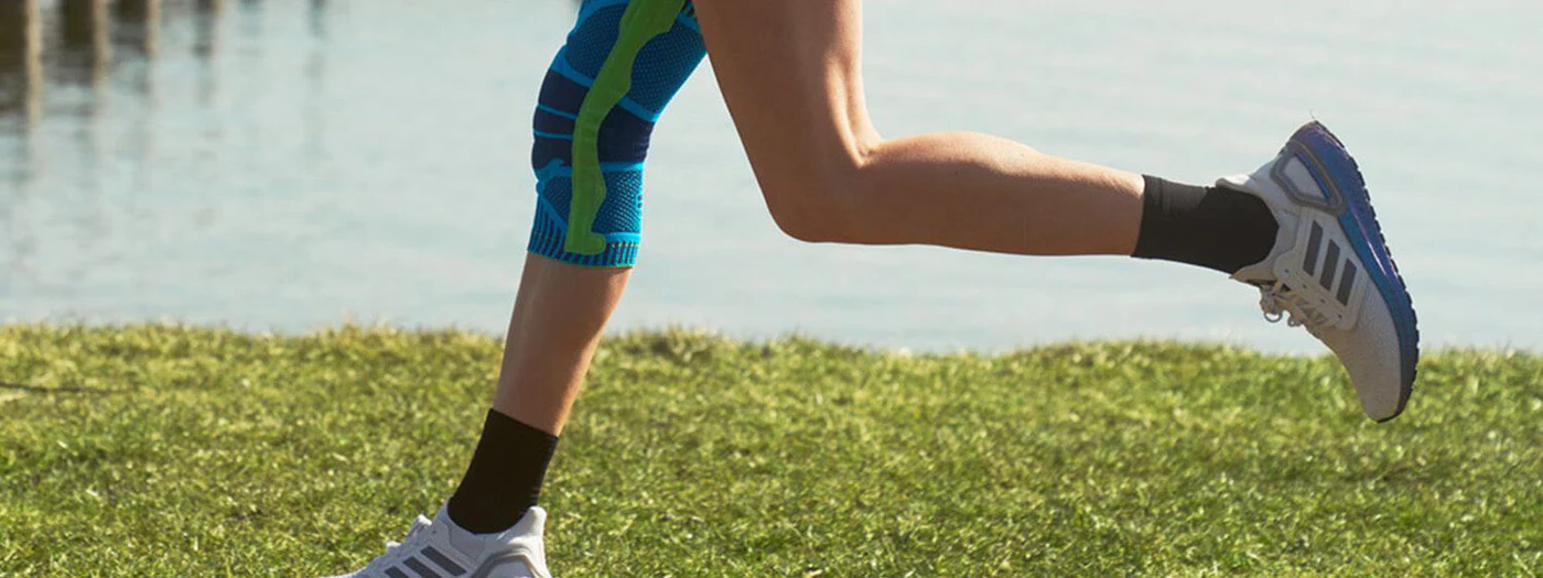 Person running near water in athletic wear and shoes.