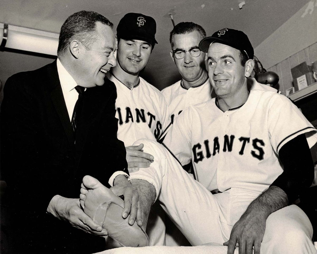 Merton L. Root holding the foot of a San Francisco Giants player