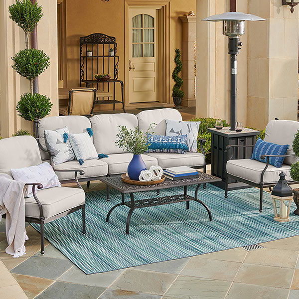 Outdoor seating area with cushions, table, and decorative plants.