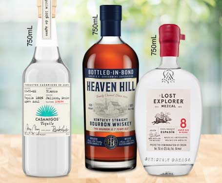 Three whiskey bottles on a wooden surface with a blurred background.
