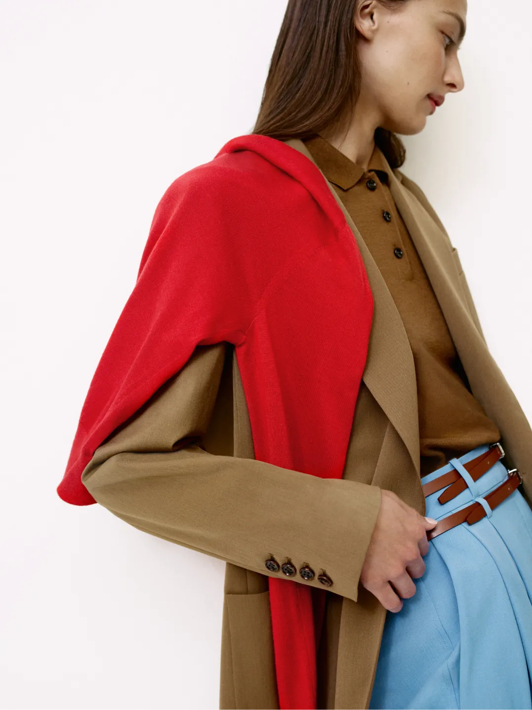 Woman wearing a red shawl over a brown blazer and blue pants.