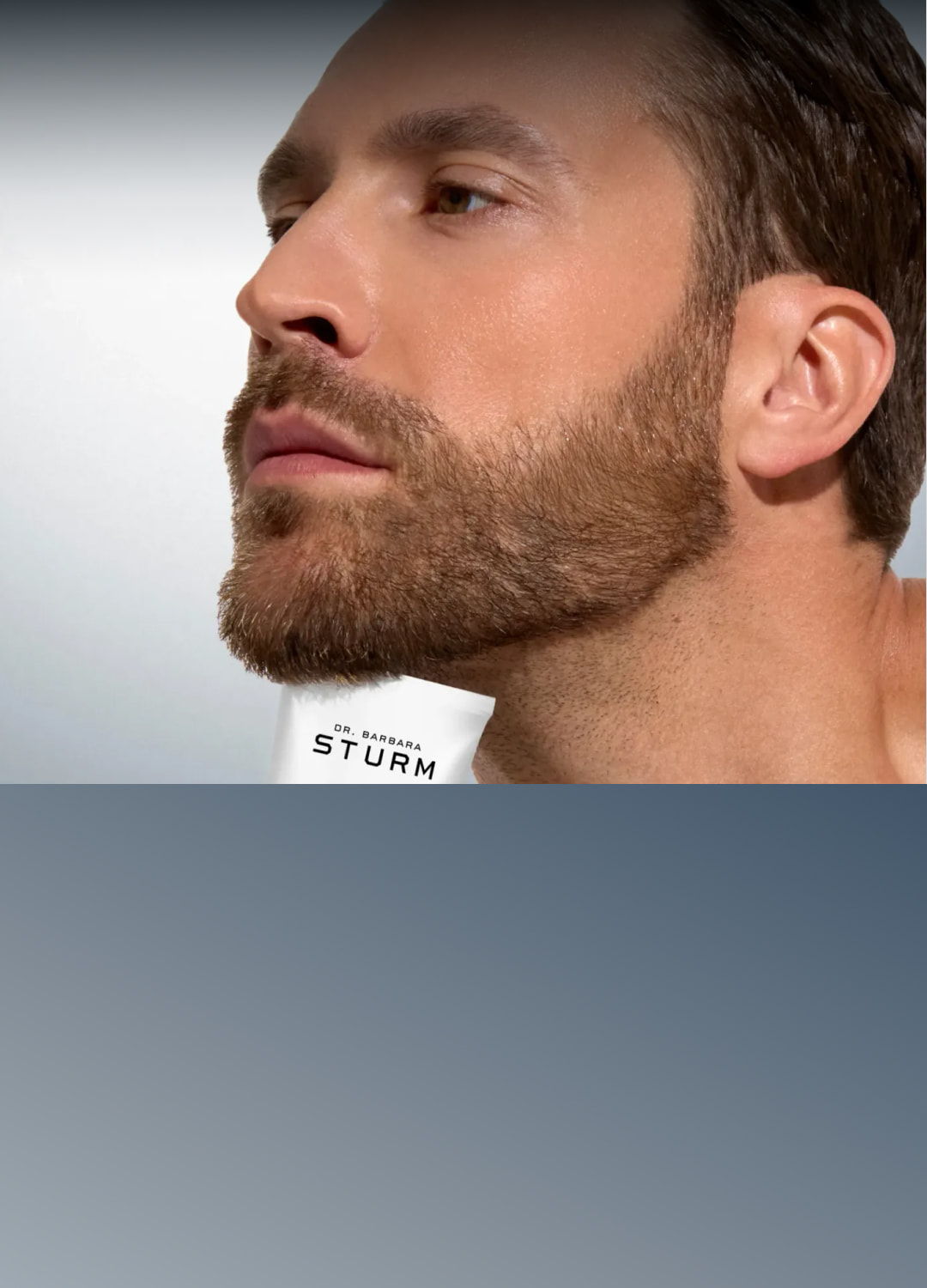 Man with a beard looking to the side, product in the background.