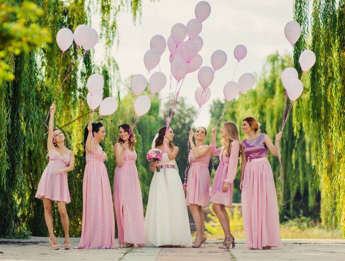Bride and bridesmaid coordinating in pink and holding pink balloons 