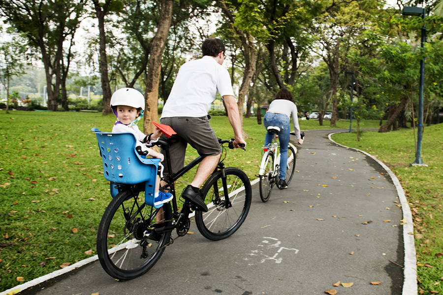 Couple biking through a park with kid in back