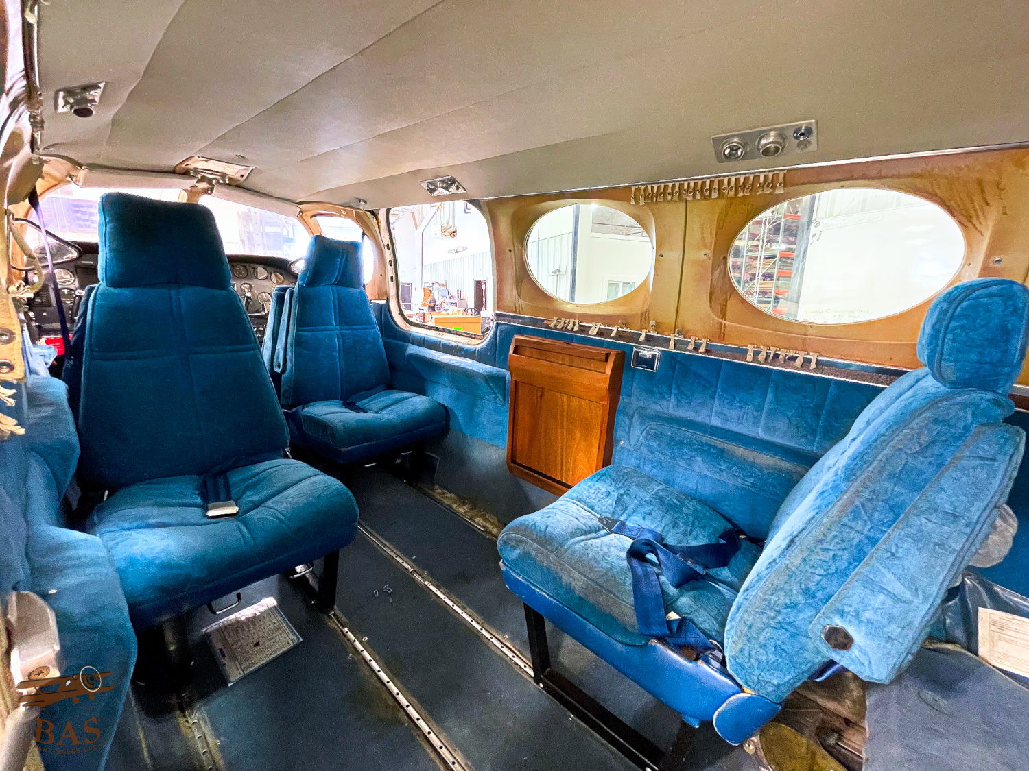 Interior of a vintage aircraft with blue seating and wooden accents.