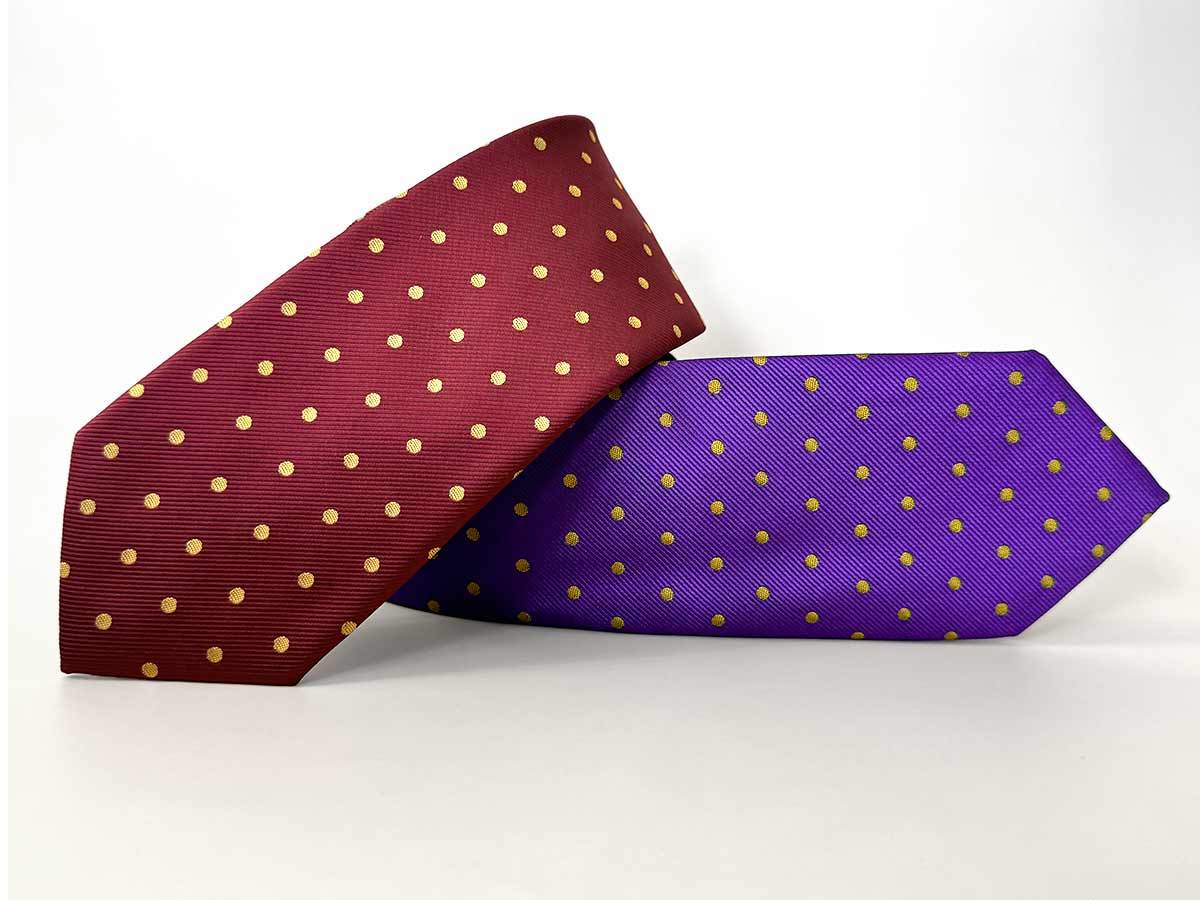 A maroon and gold and dark purple and gold polka dot tie, stacked on top of each other