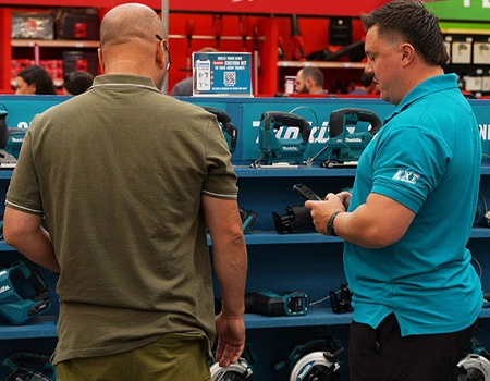 Two men examining tools in a store aisle.
