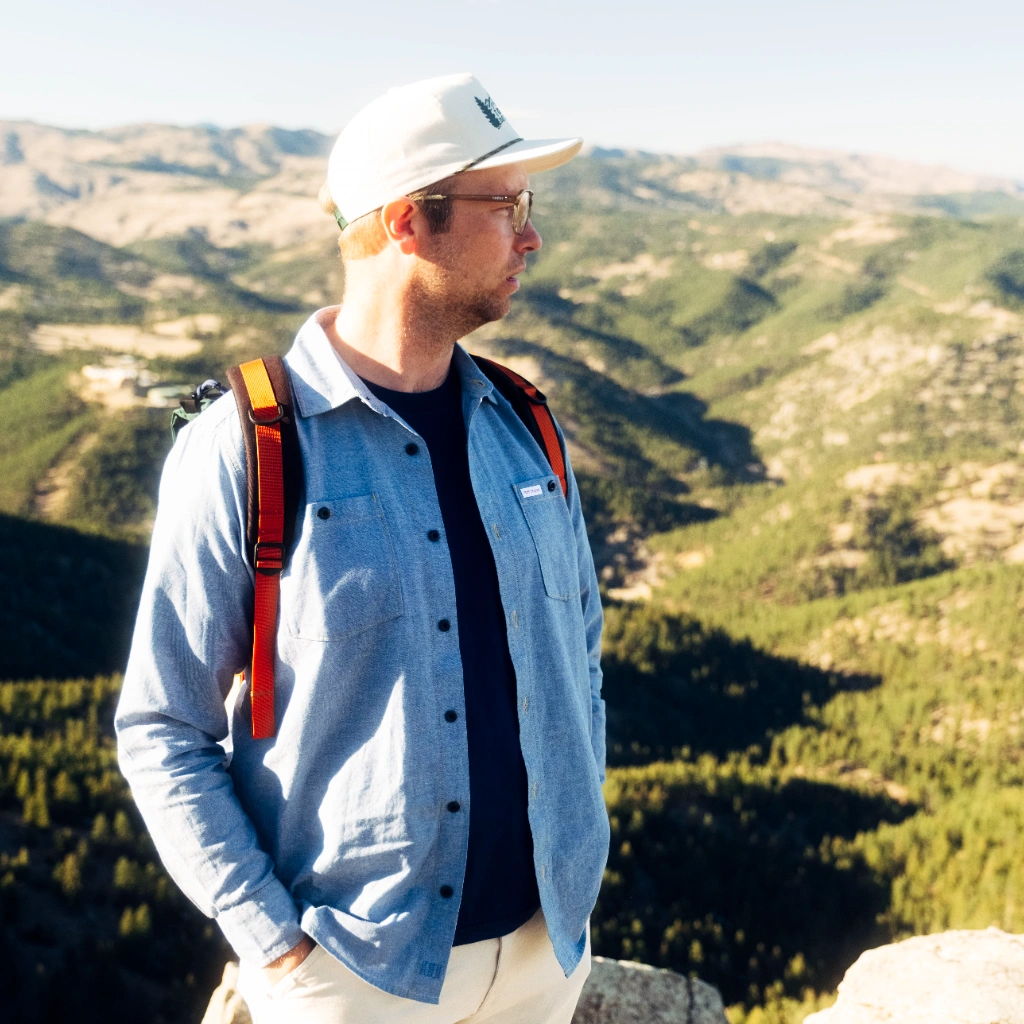 Person standing on a mountain overlooking a scenic valley.