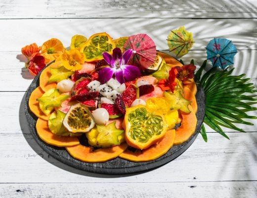 A colorful fruit platter with tropical fruits and decorative elements.