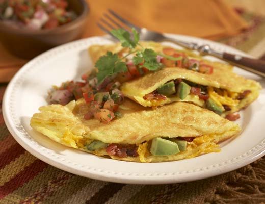 A plate of bacno and avocado omelette topped with salsa and herbs.