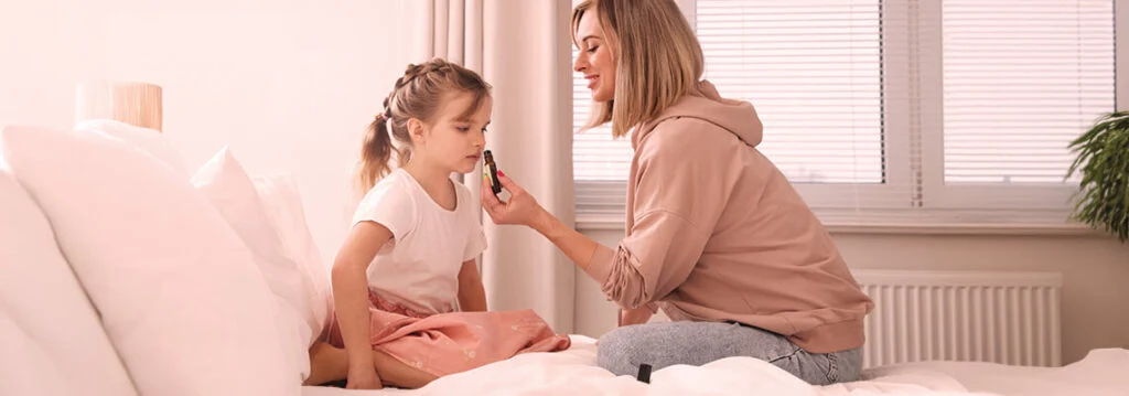 A mother and daughter playing together on a bed, smiling and enjoying each other.